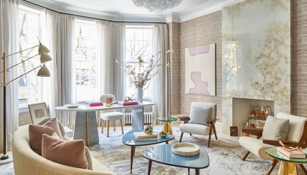 A cozy room with cushioned furniture, wall designs, coffee table, and study table with cushion stool, illuminated by pleasant light. This is a modern interior design created by Woodmax Interiors.