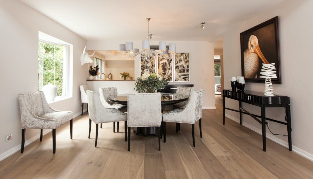 Cozy living room furnished with a comfortable couch, wooden table and chairs - Design by Woodmax Interior Designers in Mangalore