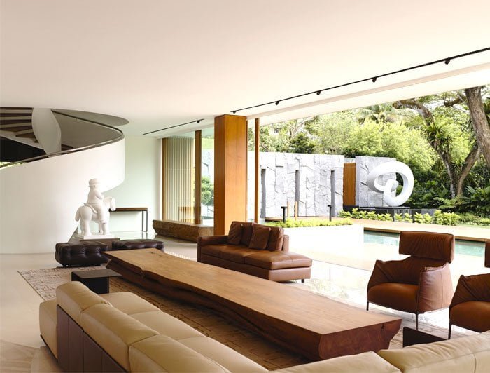 A beautifully designed outdoor space with a sofa table seamlessly connected to the interior of a house, created by interior designers in Kasaragod. The garden features lush greenery, and the table is set with decorations and accessories.